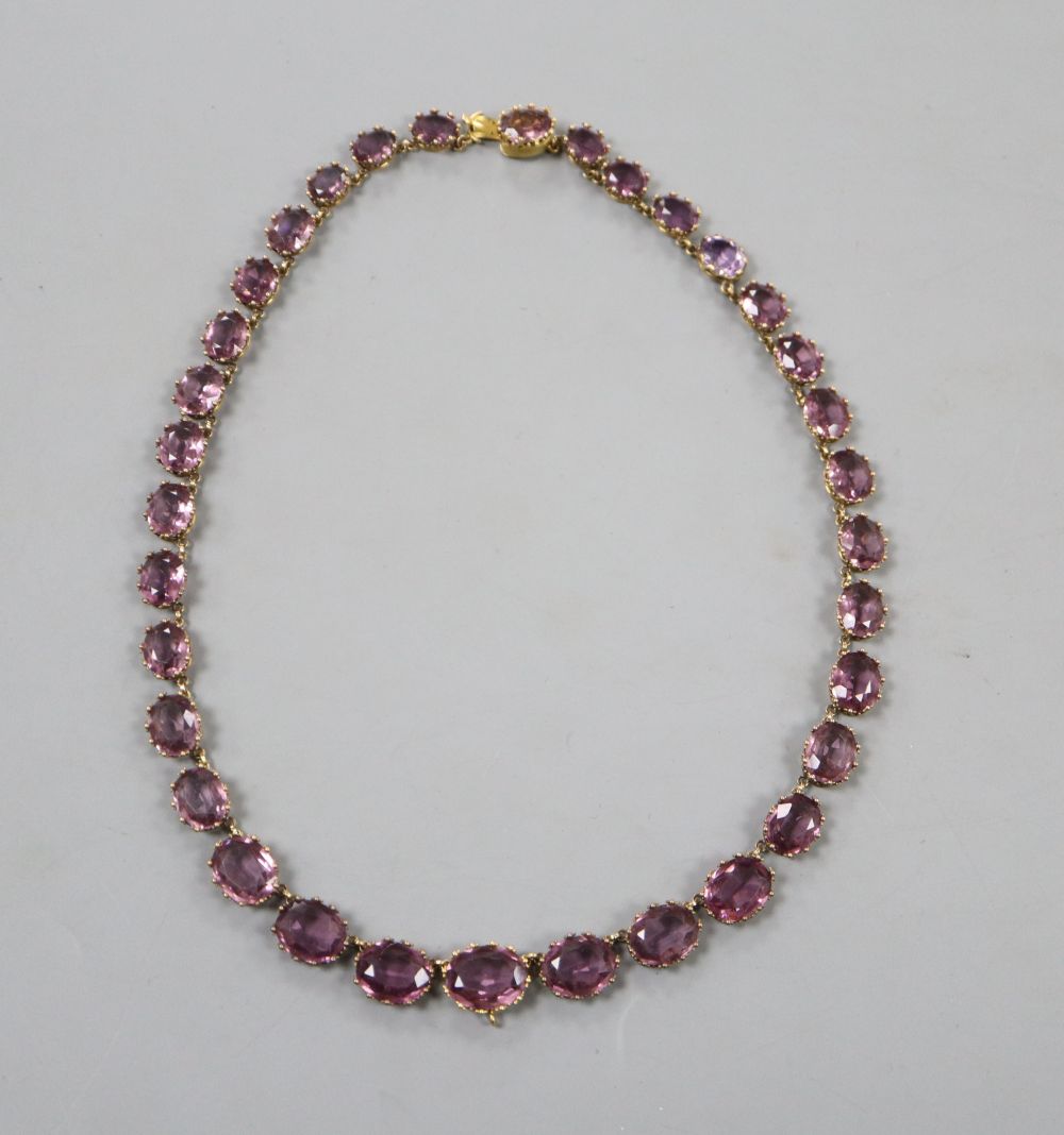 A Victorian pinchbeck and graduated amethyst coloured paste set necklace, 45.2cm, lacking central drop.